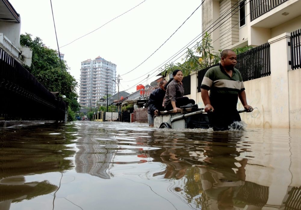 Warga melintasi permukiman yang tergenang banjir di Jakarta
